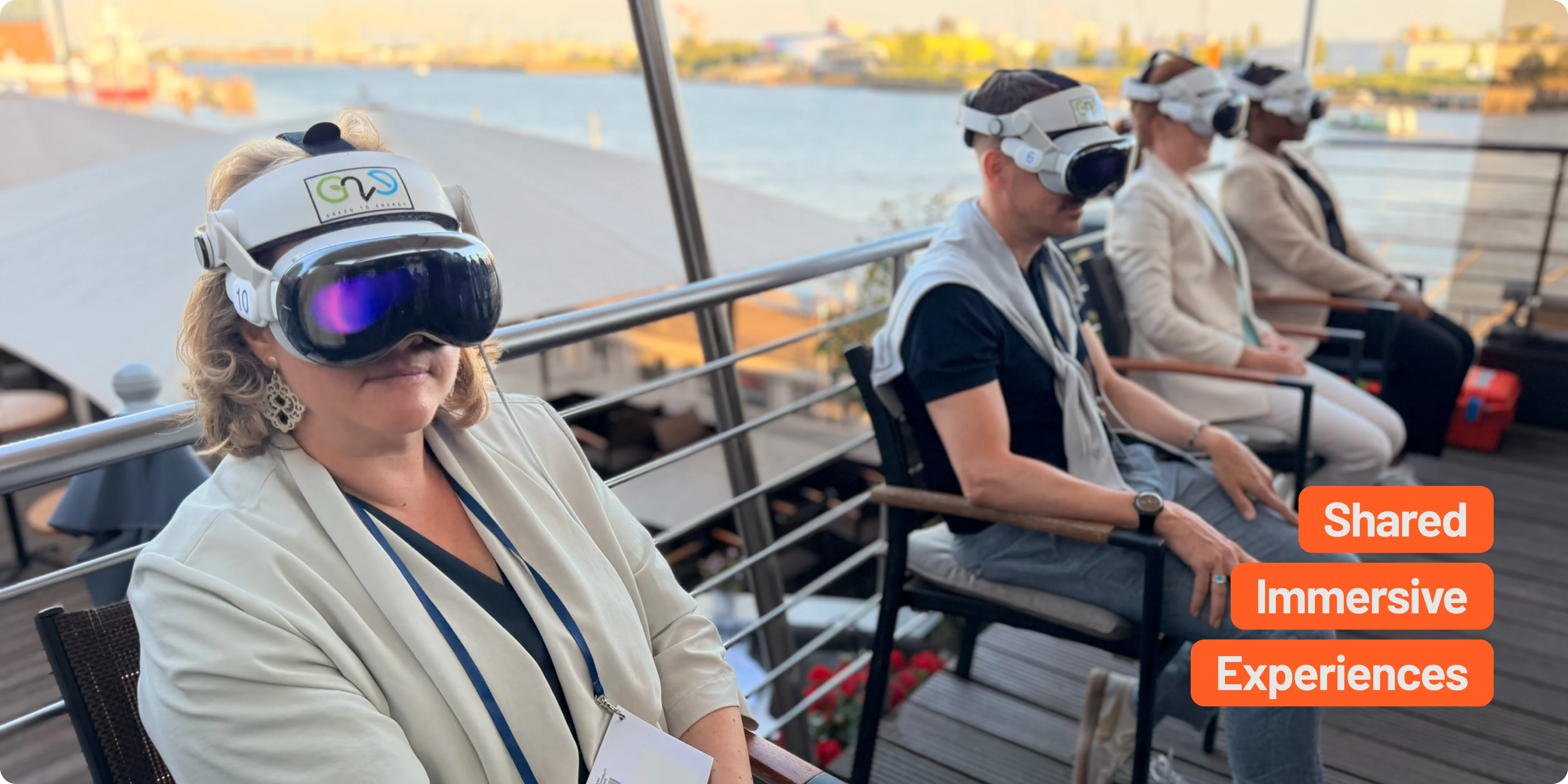 Delegates wearing Apple Vision Pro headsets during a shared immersive presentation on a waterfront terrace