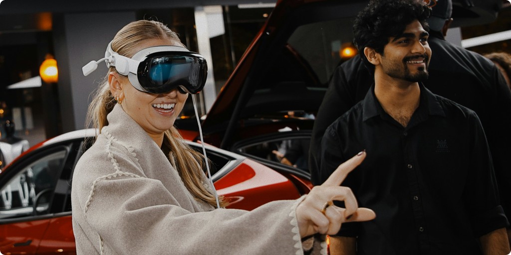 Guest wearing Apple Vision Pro in an evening showcase beside a luxury car