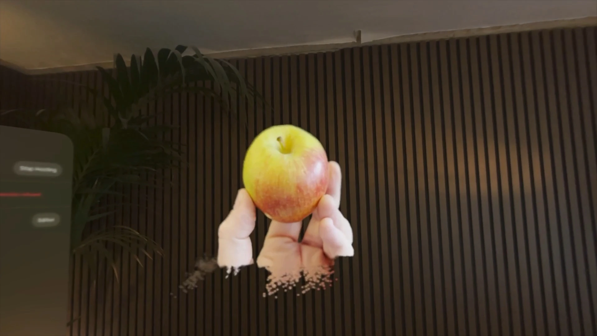 An animated Gaussian splat of a hand holding an apple in a STAGEit scene
