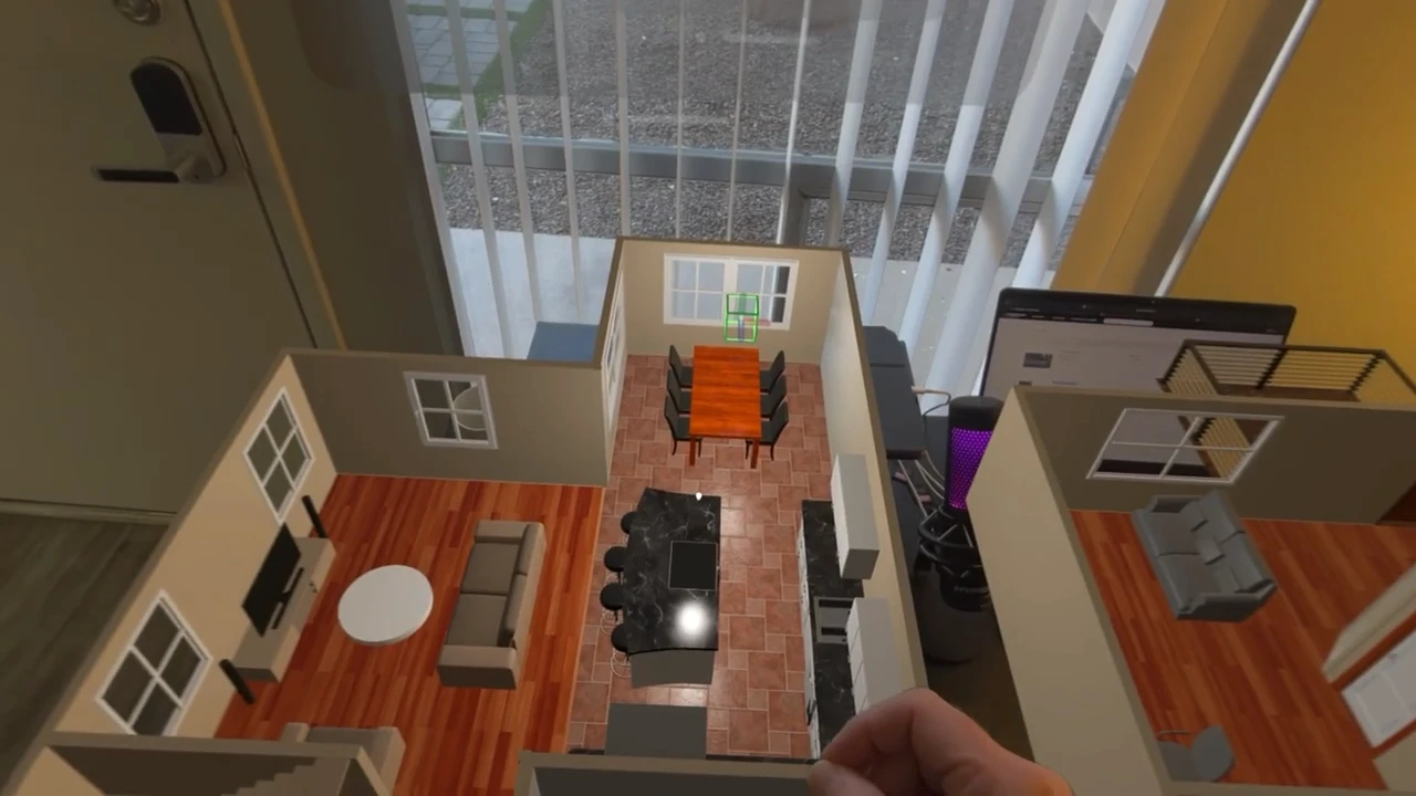 A furnished architectural model, with a kitchen, living room and dining area, being positioned by hand in STAGEit